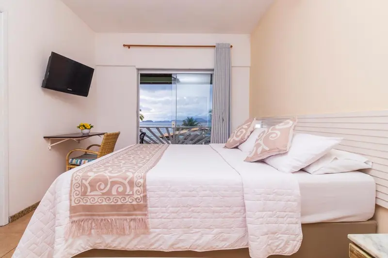 Une chambre lumineuse avec un lit recouvert d'une courtepointe et une vue sur la mer.