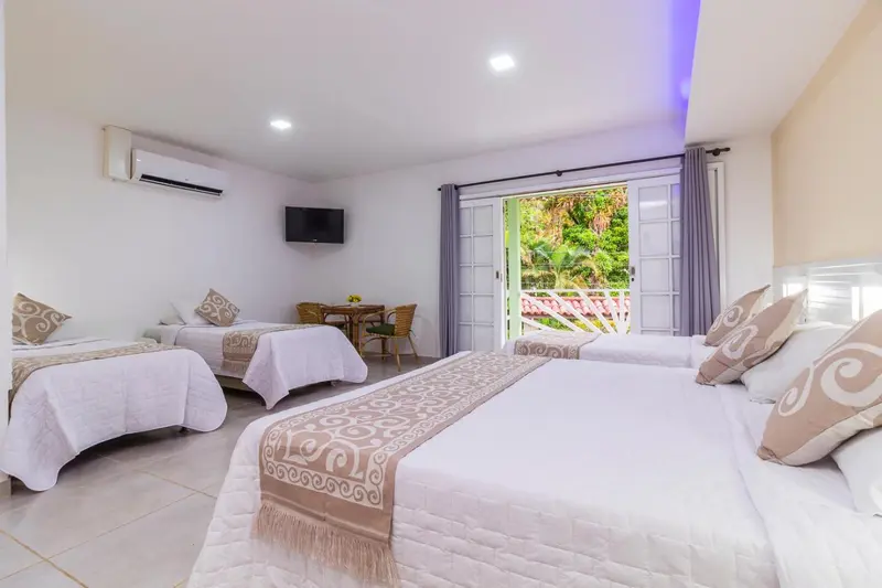 Chambre lumineuse avec deux lits et vue sur la végétation.