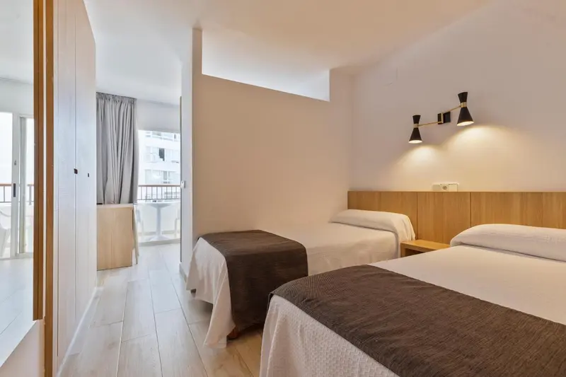 Une chambre lumineuse avec deux lits simples et un accès à un balcon.