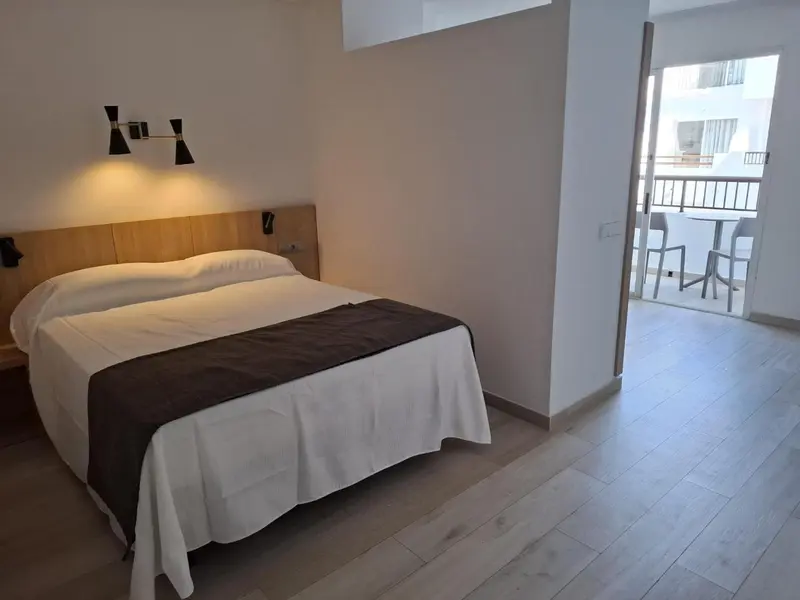 Une chambre lumineuse avec un grand lit et un accès à une terrasse.