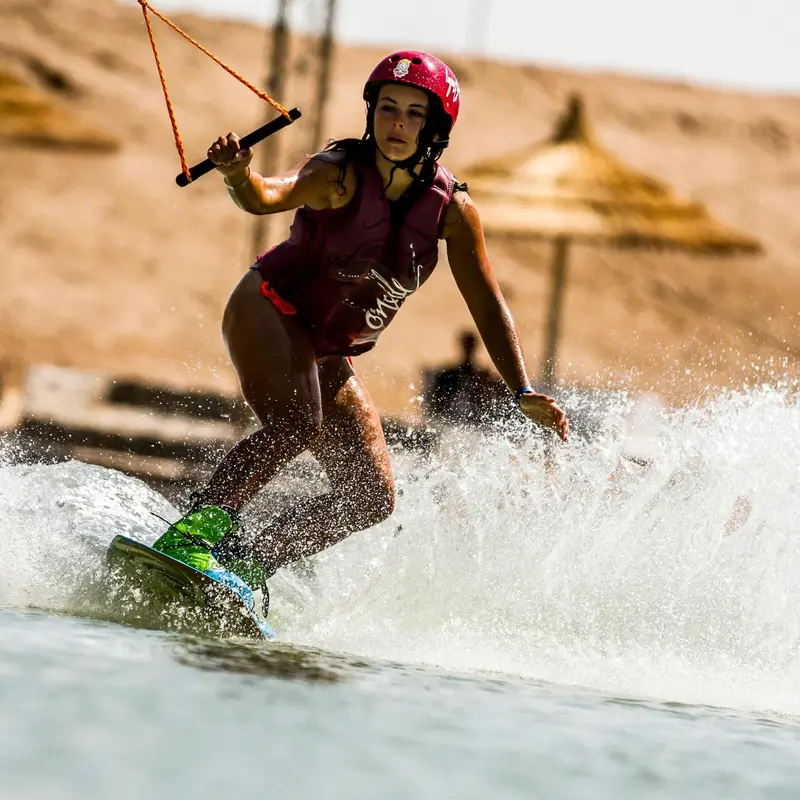 Une personne pratique le wakeboard sur une eau turquoise.