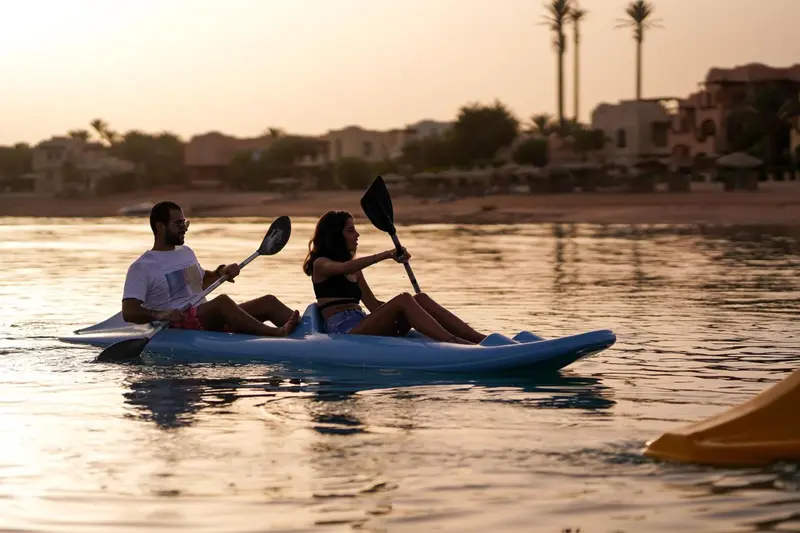 Un couple navigue en kayak sur une mer calme au coucher du soleil.