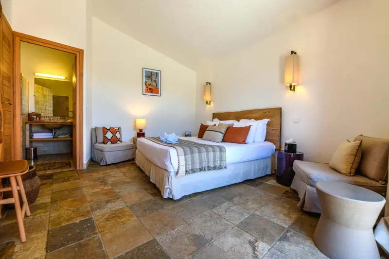 Une chambre lumineuse avec un grand lit et un coin salon.
