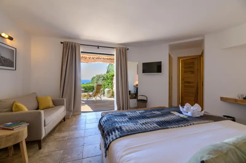Une chambre lumineuse s'ouvre sur une terrasse avec vue sur la mer.