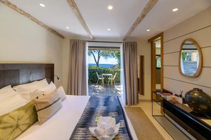 Une chambre lumineuse s'ouvre sur une terrasse avec vue sur la mer.