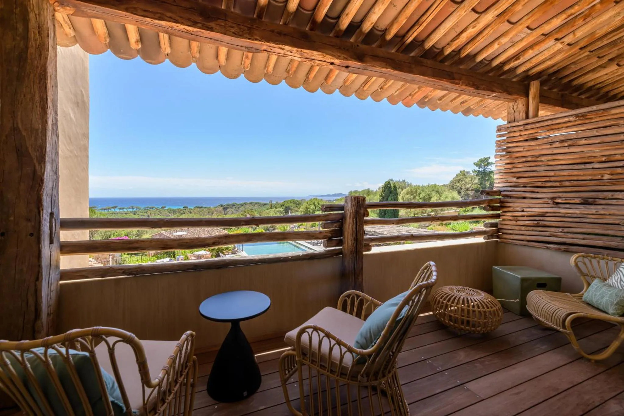 Terrasse aménagée avec mobilier en rotin et vue sur la mer.