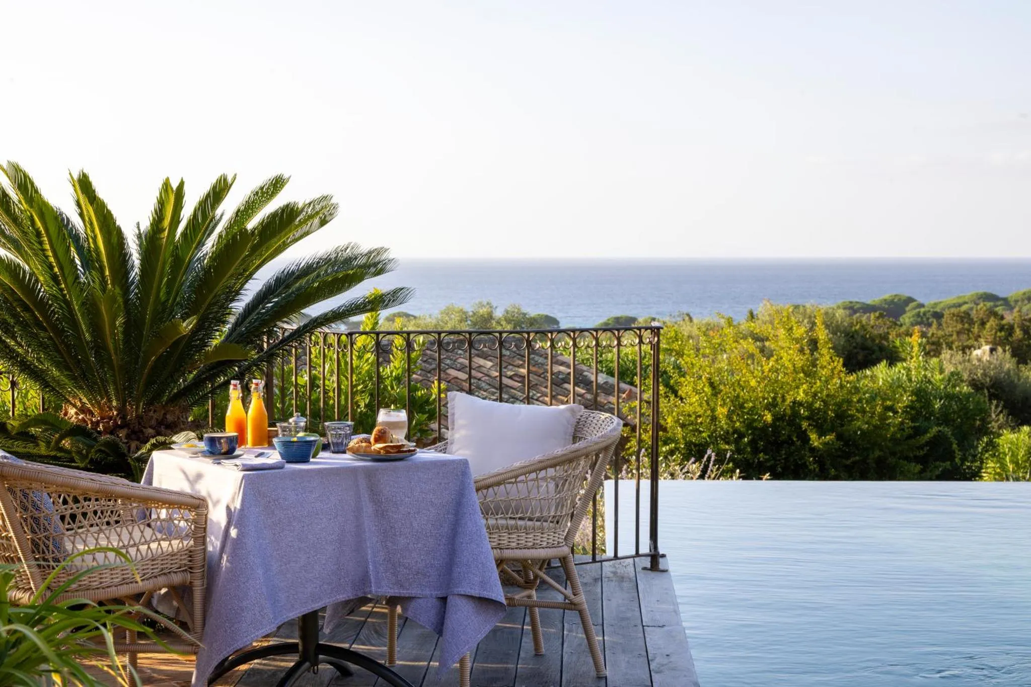 Une table de petit-déjeuner est dressée sur une terrasse avec vue sur la mer.