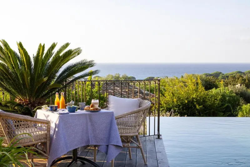 Une table de petit-déjeuner est dressée sur une terrasse avec vue sur la mer.