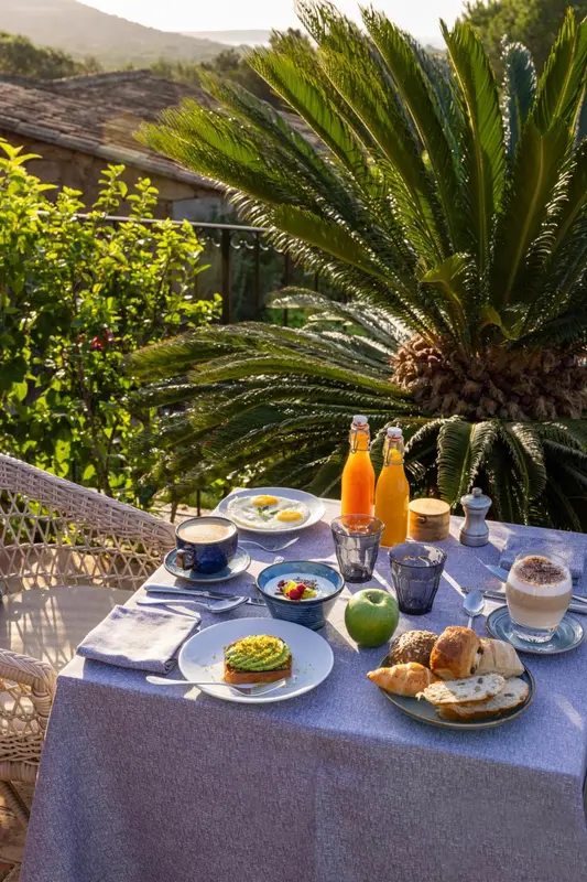 Une table est dressée pour un petit-déjeuner avec des œufs, des fruits et des boissons.