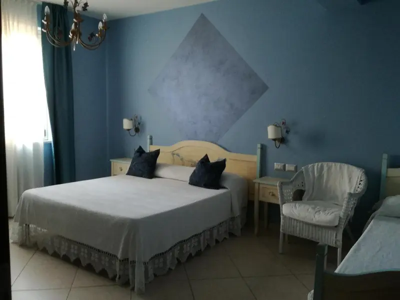 Une chambre lumineuse avec un lit double et un fauteuil.