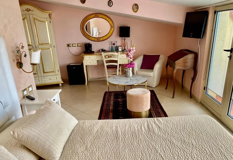 Une chambre lumineuse avec un lit, un bureau et un coin salon.