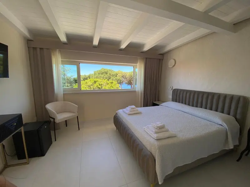 Une chambre lumineuse avec un grand lit et une vue sur la végétation.