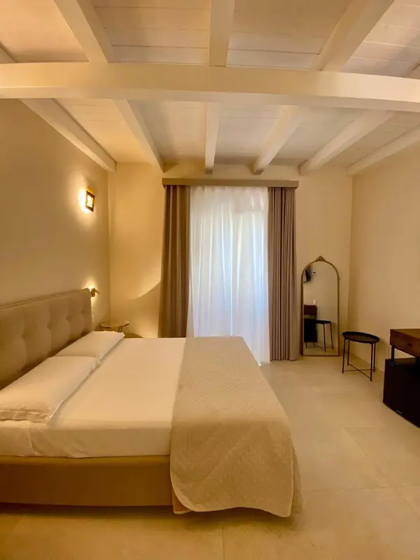 Une chambre lumineuse avec un grand lit et un miroir.