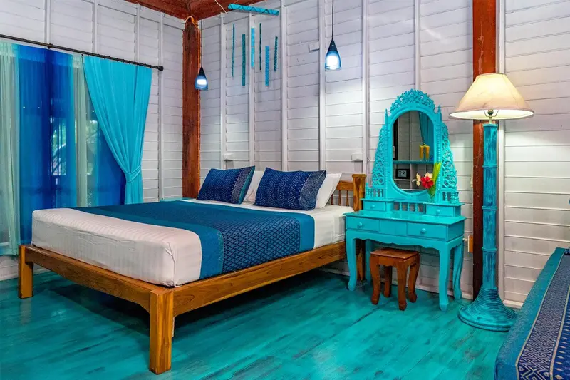 Une chambre lumineuse avec un lit recouvert d'une courtepointe bleue et de coussins assortis.