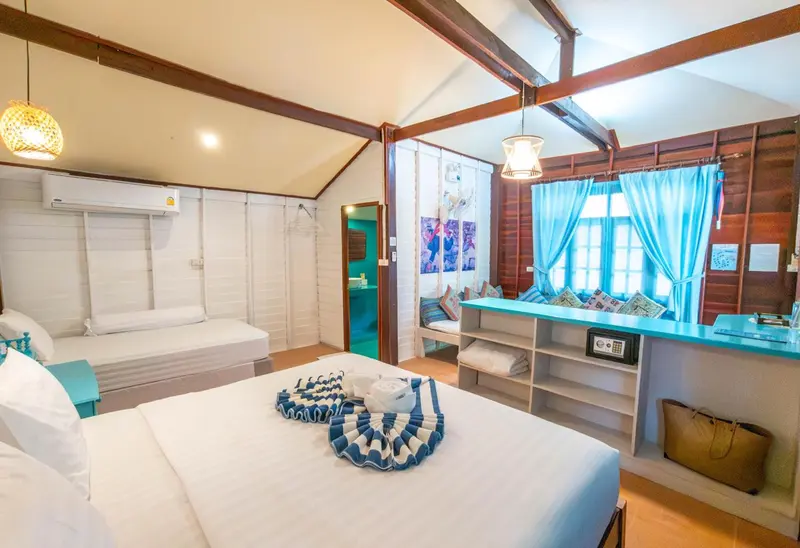 Chambre lumineuse avec lit double et coin salon turquoise.