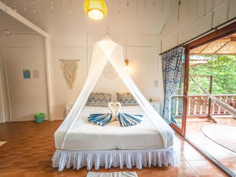 Une chambre lumineuse avec un lit à baldaquin donnant sur une terrasse.