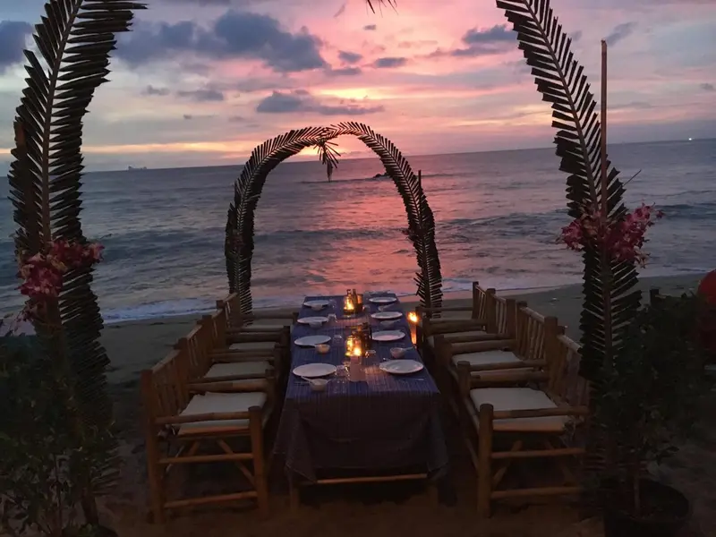 Table dressée sur une plage au coucher du soleil.