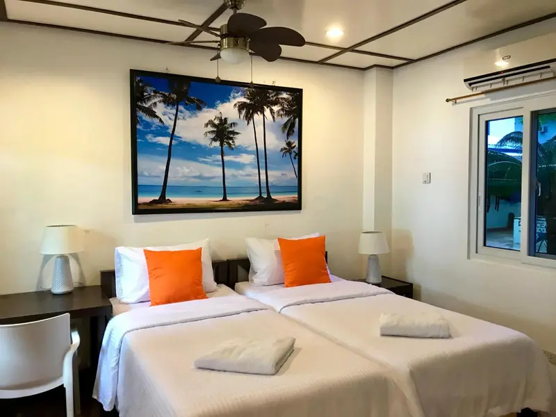 Une chambre lumineuse avec deux lits simples et une décoration tropicale.