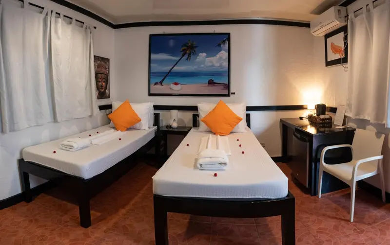 Une chambre lumineuse avec deux lits simples et un bureau.