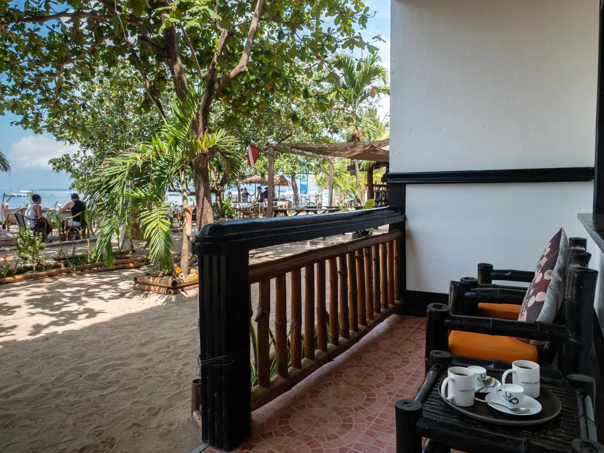 Terrasse ombragée avec mobilier de jardin et vue sur la mer.