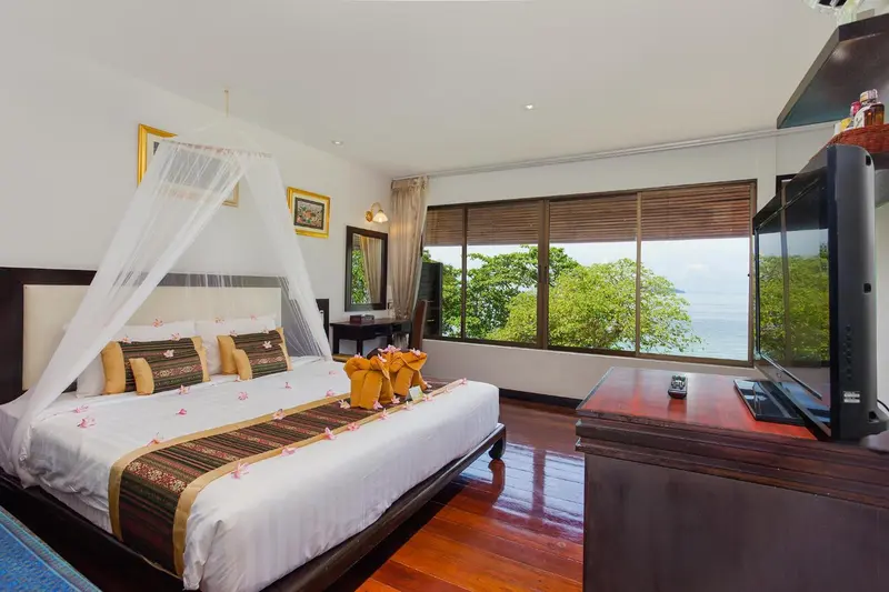 Une chambre lumineuse avec un grand lit à baldaquin et une vue sur la mer.