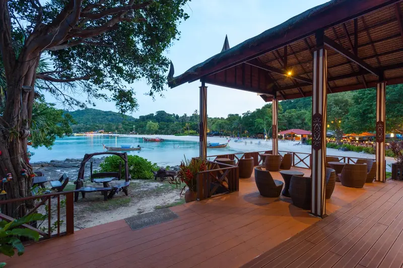 Terrasse ombragée avec mobilier de détente donnant sur une baie.