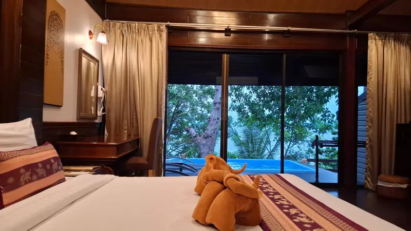 Une chambre avec un lit et une vue sur une piscine et la végétation.