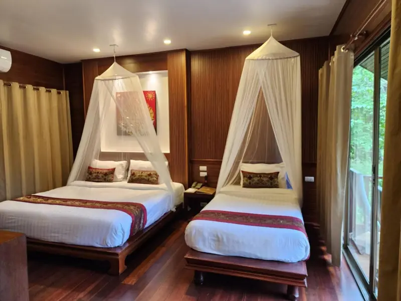 Deux lits jumeaux avec moustiquaires dans une chambre décorée de bois.