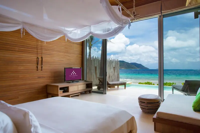 Une chambre lumineuse s'ouvre sur une vue dégagée sur la mer turquoise.