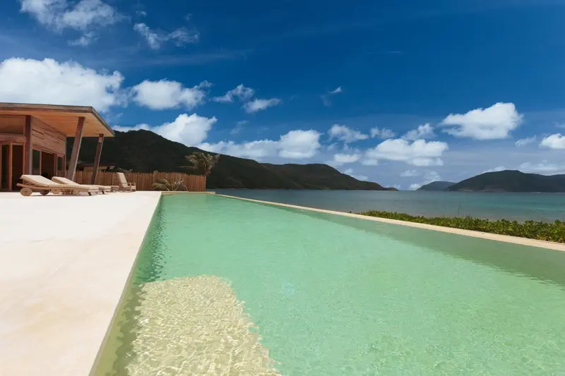 Une piscine à débordement offre une vue sur la mer et les collines verdoyantes.