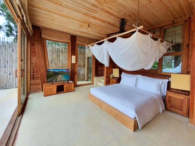 Une chambre lumineuse avec un grand lit à baldaquin et une télévision.