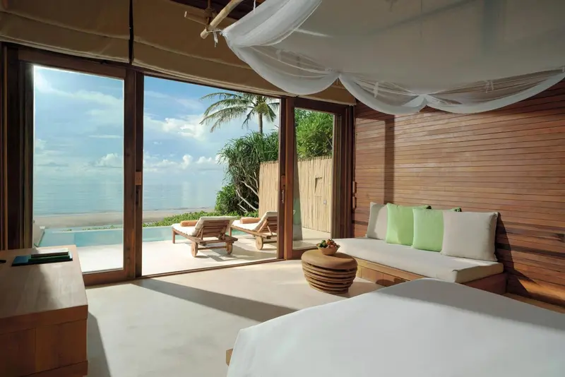 Une chambre lumineuse s'ouvre sur une terrasse avec piscine et vue sur la mer.