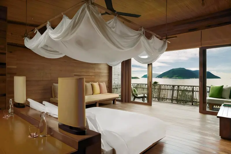 Une chambre lumineuse avec un lit à baldaquin donnant sur une vue mer.