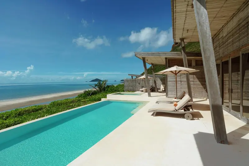 Une piscine turquoise bordée d'une terrasse ensoleillée avec des transats.