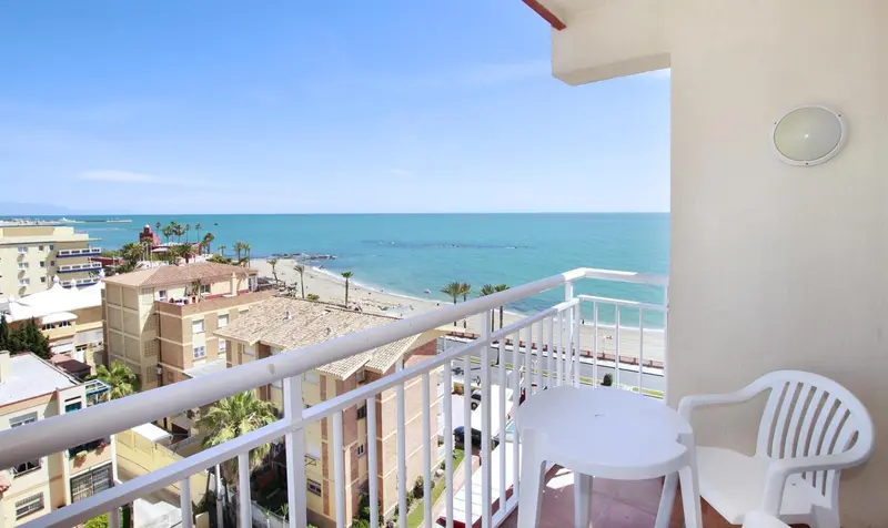 Vue d'une terrasse avec une table et des chaises donnant sur la mer et la ville.