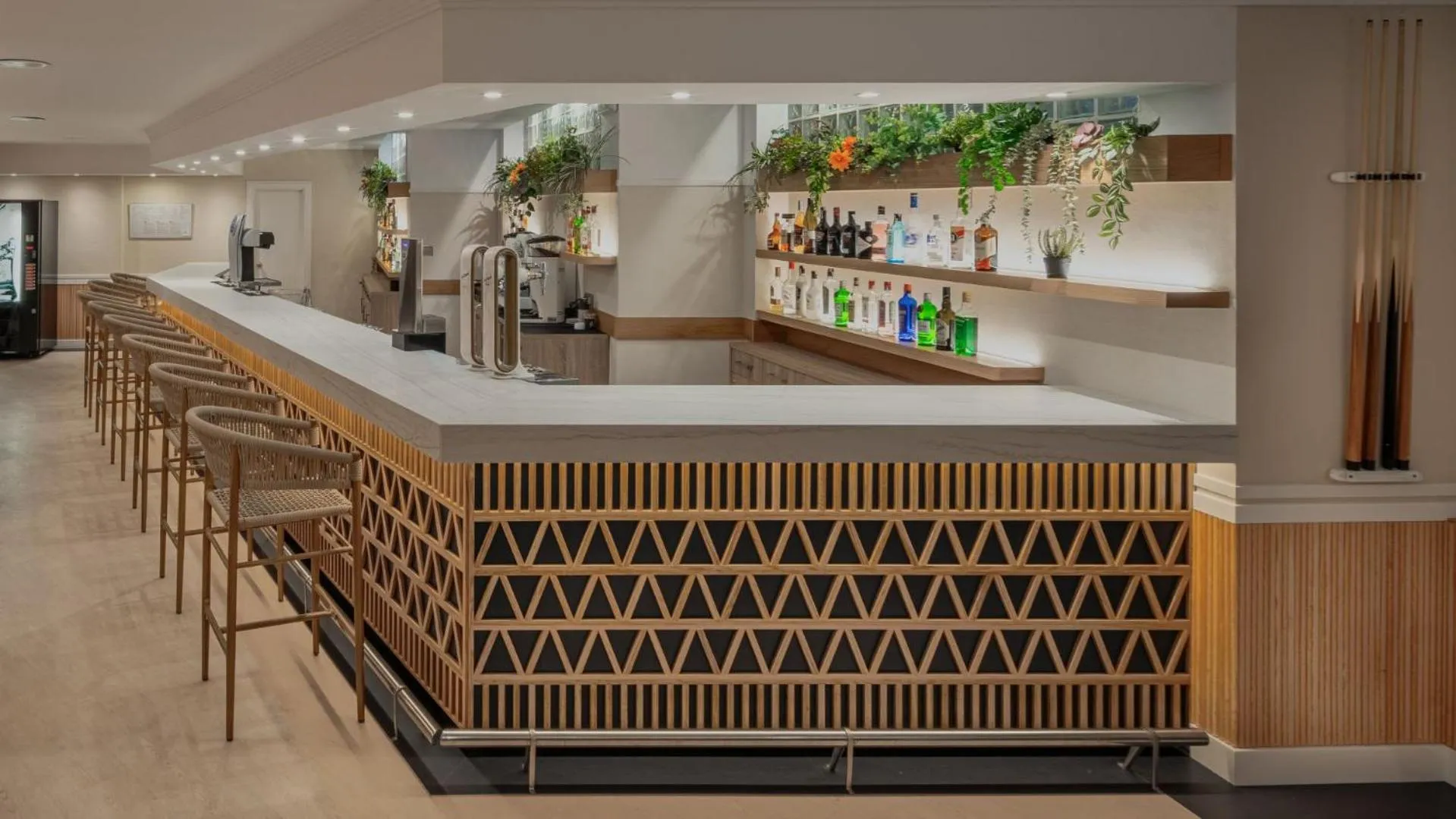 Un comptoir de bar moderne avec des tabourets et une sélection de boissons.