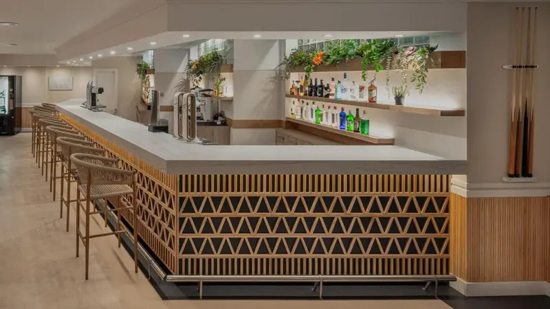 Un comptoir de bar moderne avec des tabourets et une sélection de boissons.