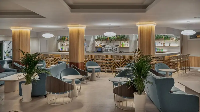 Un espace de détente avec des canapés et des fauteuils face à un long comptoir de bar.