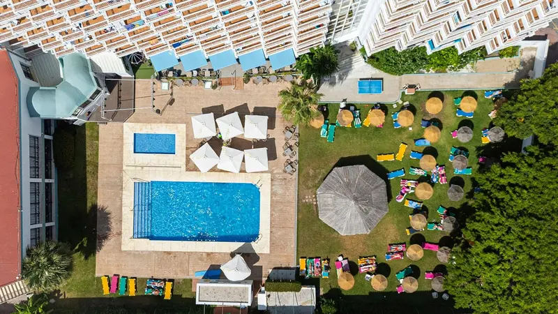 Vue aérienne d'une piscine et d'un espace de détente avec transats et parasols.