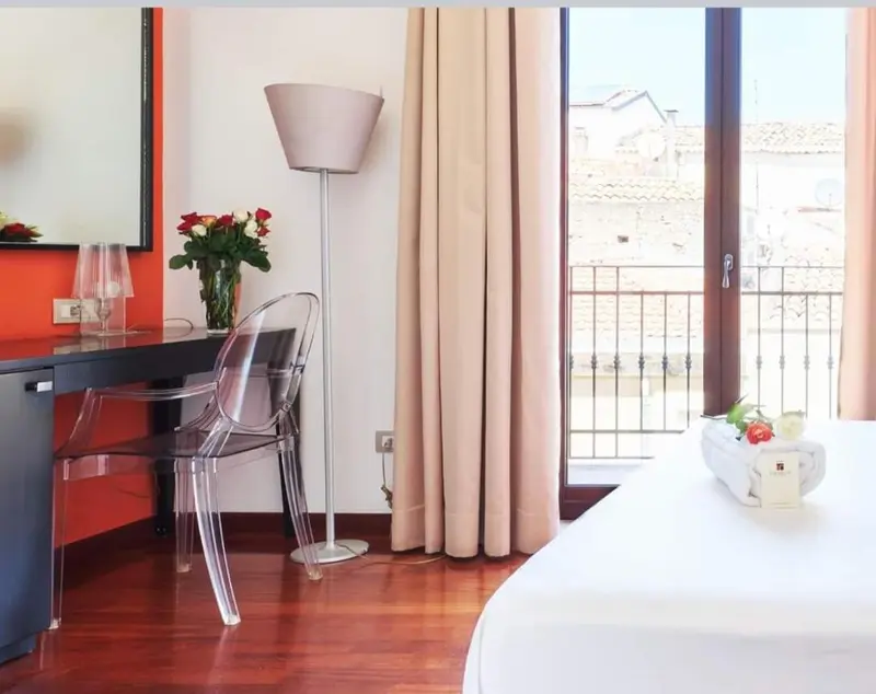 Une chambre lumineuse avec un bureau et un accès à un balcon.