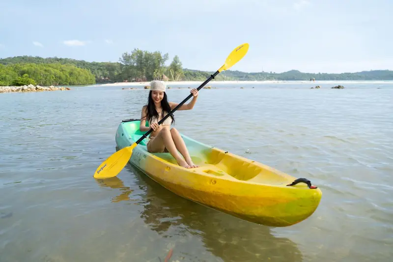 Une jeune femme pratique le kayak sur une mer calme.