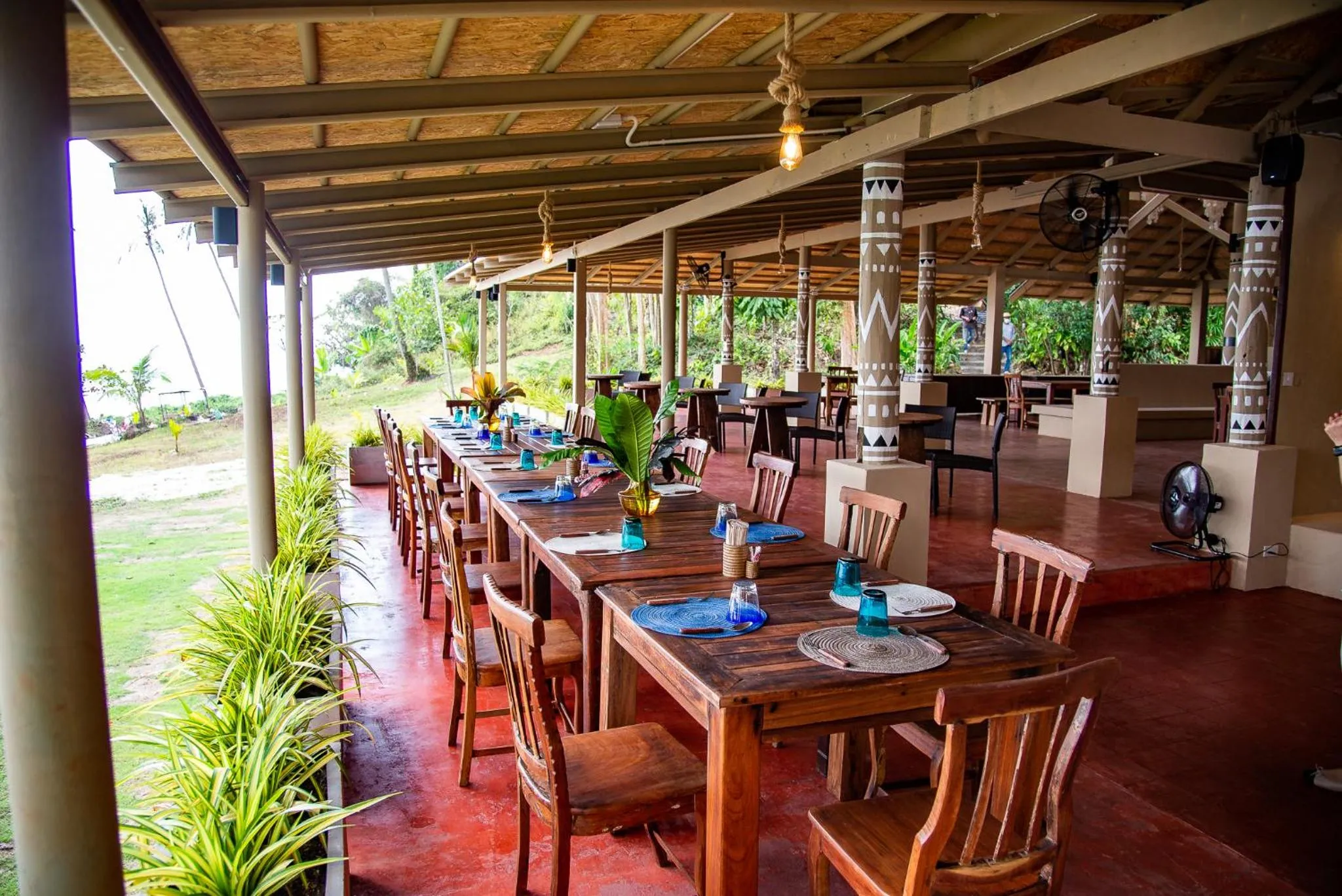 Une salle à manger extérieure avec des tables en bois et des chaises.