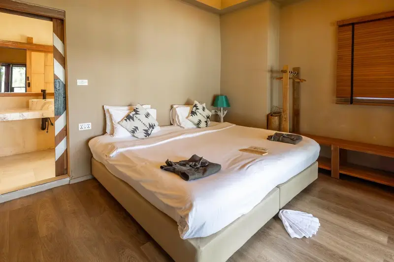 Une chambre lumineuse avec un grand lit recouvert d'une courtepointe blanche et de coussins.