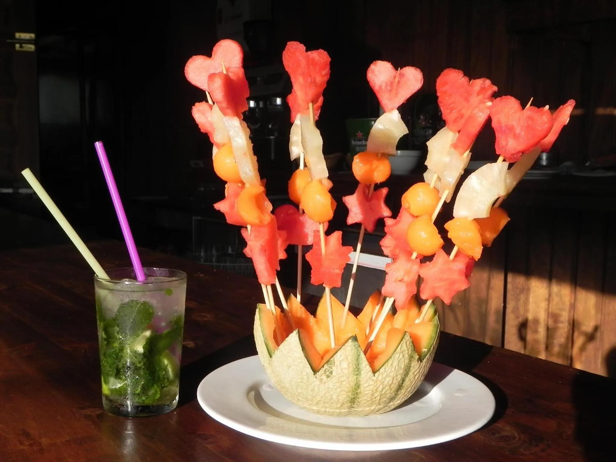 Une présentation de fruits frais et un cocktail sont disposés sur une table.