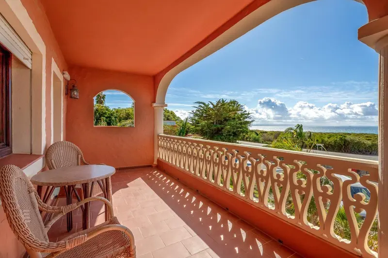 Terrasse avec mobilier en osier donnant sur un paysage côtier.