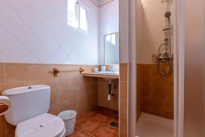 Une salle de bain carrelée avec douche, lavabo et toilettes.