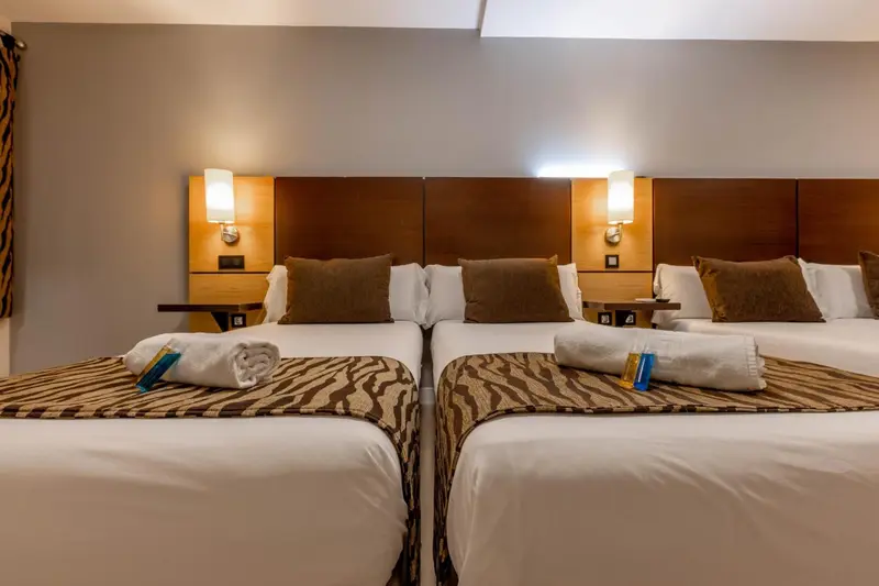 Deux lits jumeaux avec oreillers et couvertures dans une chambre d'hôtel.