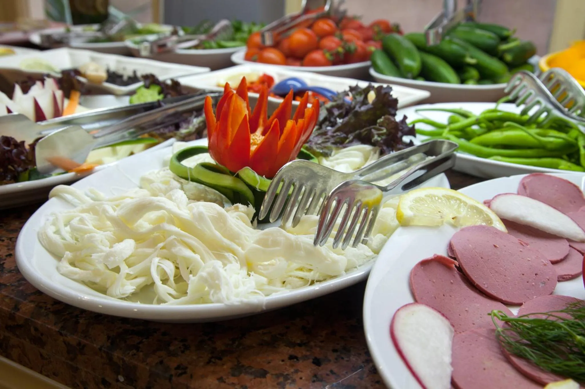 Un buffet propose une variété de salades, de légumes et de charcuteries.