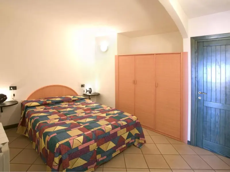 Une chambre à coucher avec un lit recouvert d'une courtepointe colorée et une grande armoire.