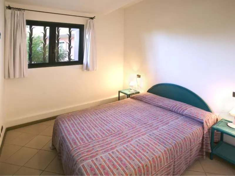 Une chambre lumineuse avec un lit recouvert d'une courtepointe et une fenêtre.